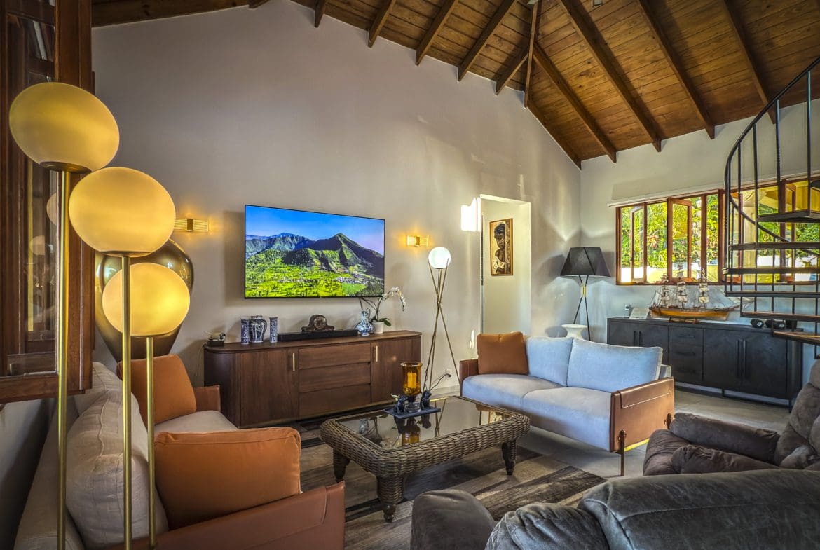 buyDRproperty Living room in a luxury villa with ocean views, featuring sofas, a TV, and a spiral staircase. Sosua Real Estate