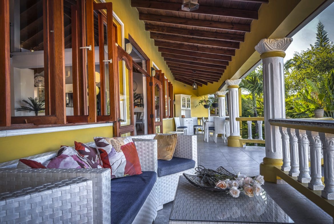 buyDRproperty Luxury villa veranda with white wicker furniture and open windows. Enjoying ocean views from this villa for sale. Sosua Real Estate