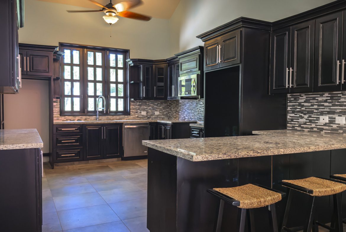 buyDRproperty Modern kitchen design with black cabinets, granite countertops, and bar seating. Sosua Real Estate