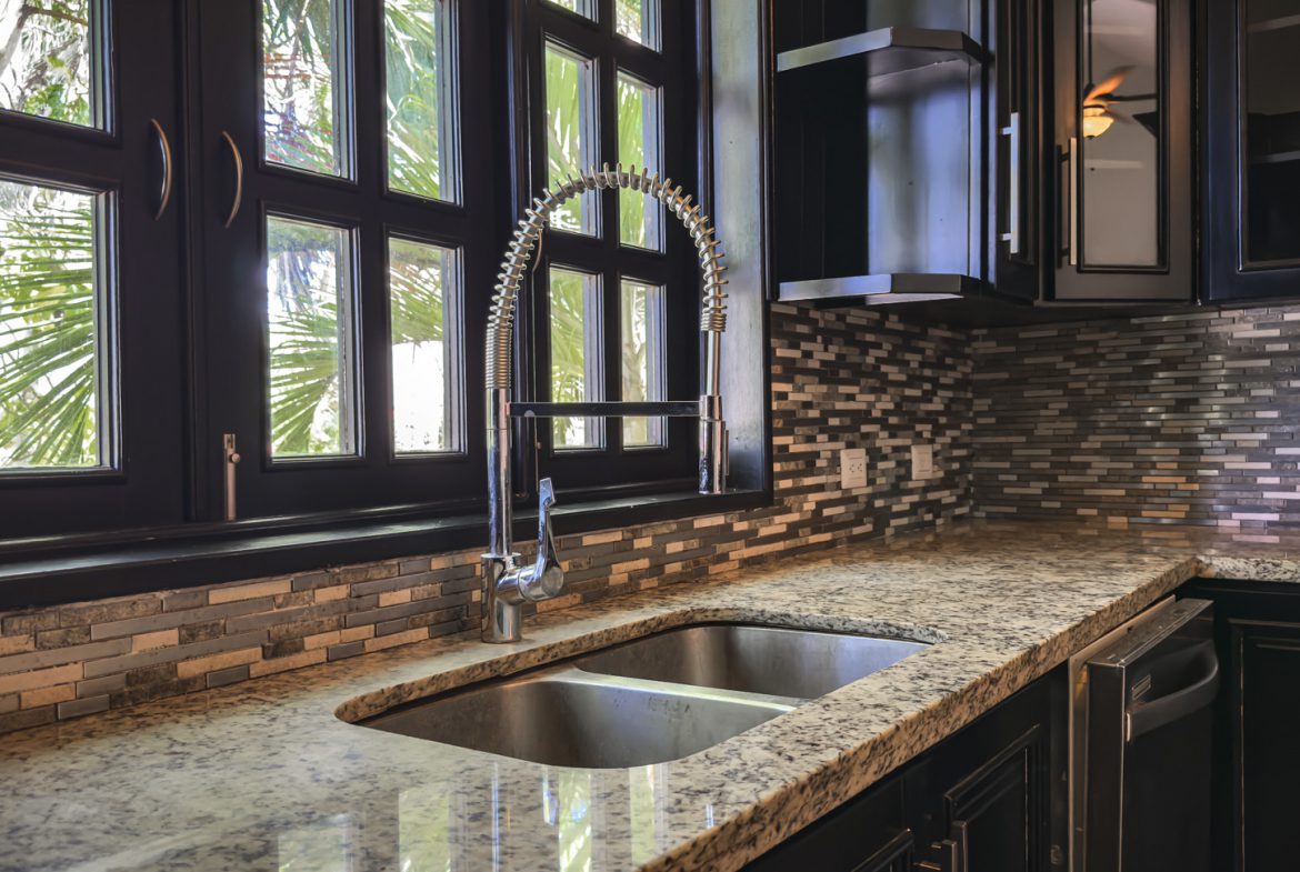 buyDRproperty Modern kitchen remodel with black cabinets, granite countertops, and stainless steel faucet. Sosua Real Estate