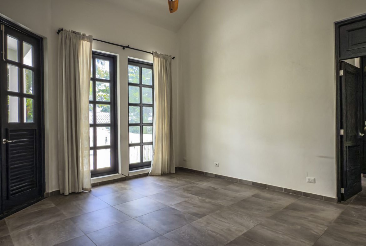 buyDRproperty Empty room with black doors, windows, and neutral curtains, ready for home design. Sosua Real Estate