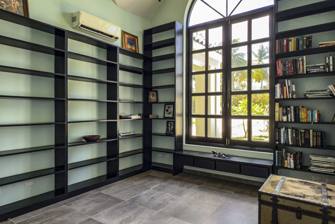 buyDRproperty Home library with black bookshelves, a large window, and a vintage trunk. Sosua Real Estate