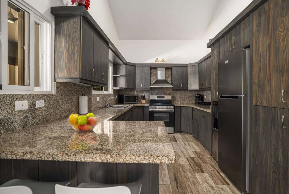 buyDRproperty Elegant kitchen with dark wood cabinets and granite countertops in Villa Lotus. Sosua Real Estate