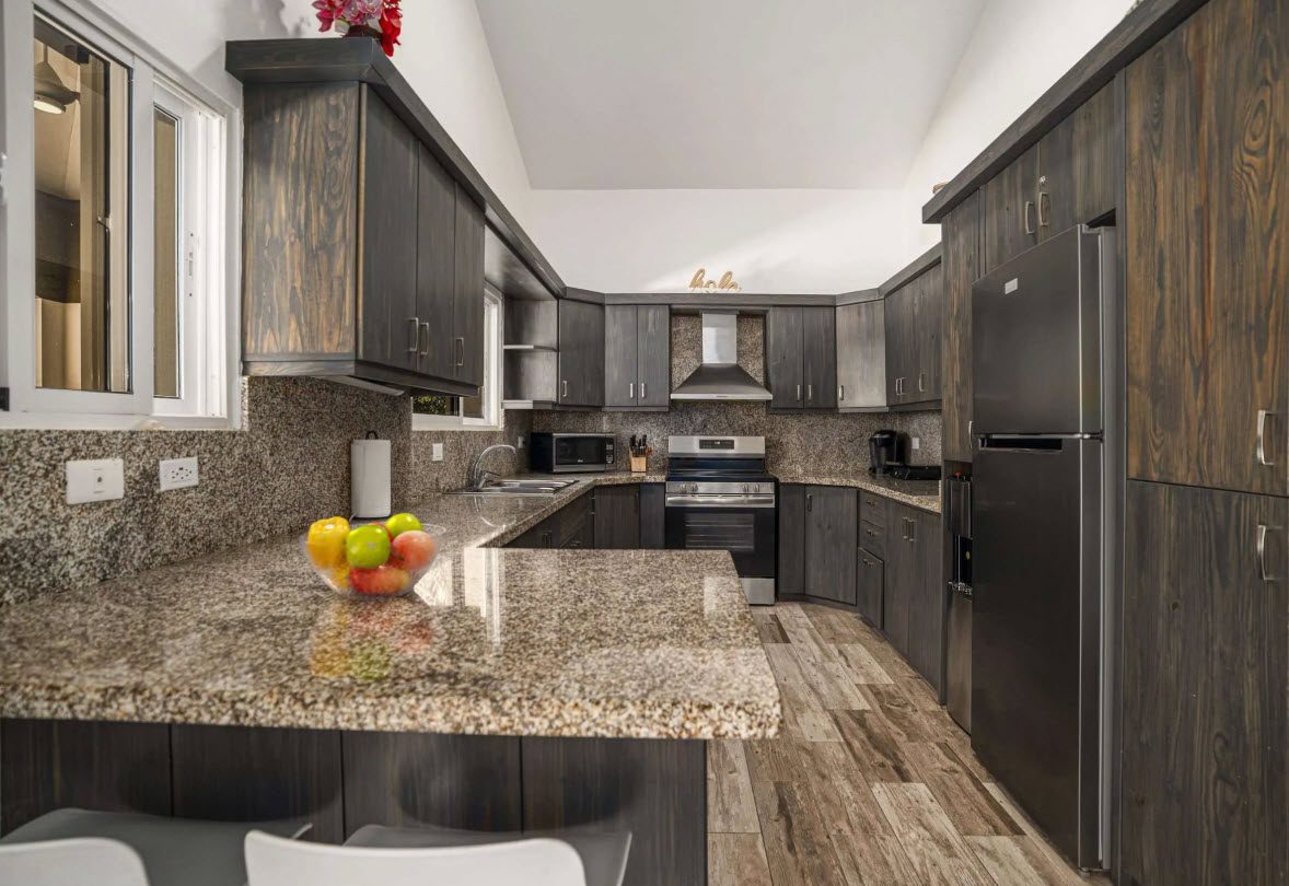buyDRproperty Elegant kitchen with dark wood cabinets and granite countertops in Villa Lotus. Sosua Real Estate