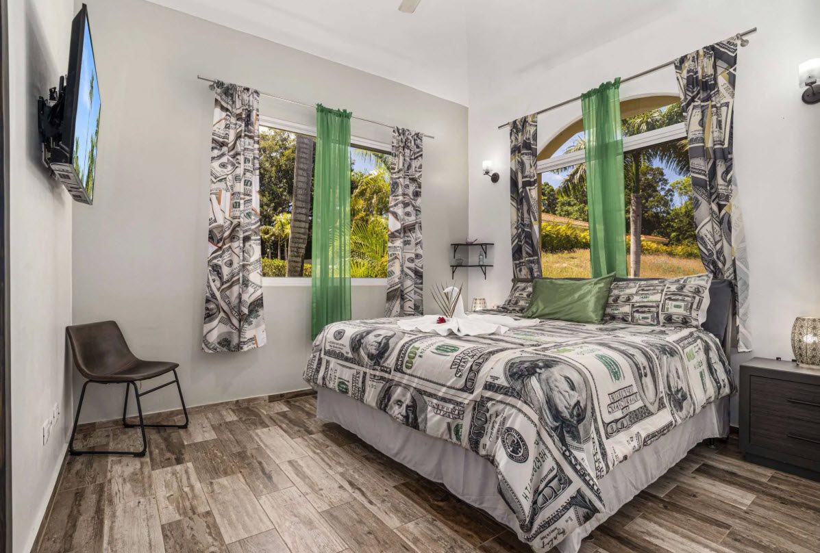 buyDRproperty Elegant bedroom in Villa Lotus with dollar bill-themed bedding and green curtains. Sosua Real Estate
