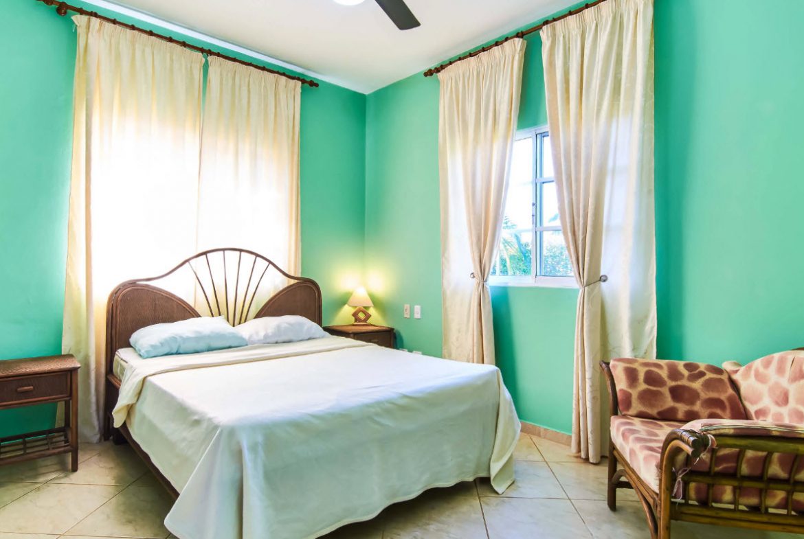 buyDRproperty Bedroom in a villa for sale in Residential Hispaniola with a bed, window, and sofa. Sosua Real Estate