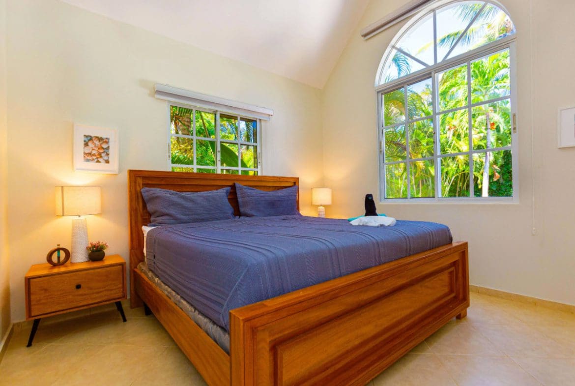buyDRproperty Bedroom in a 3 BR Villa with a large wooden bed and bright windows Sosua Real Estate