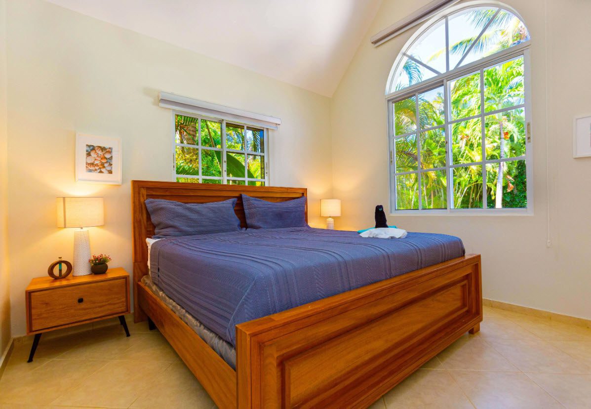 buyDRproperty Bedroom in a 3 BR Villa with a large wooden bed and bright windows Sosua Real Estate