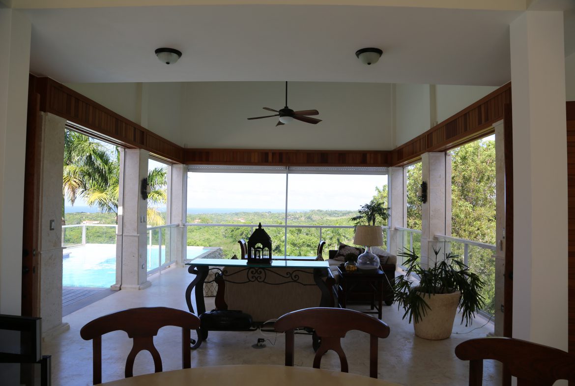 buyDRproperty Spacious living room with pool view and lush greenery Sosua Real Estate