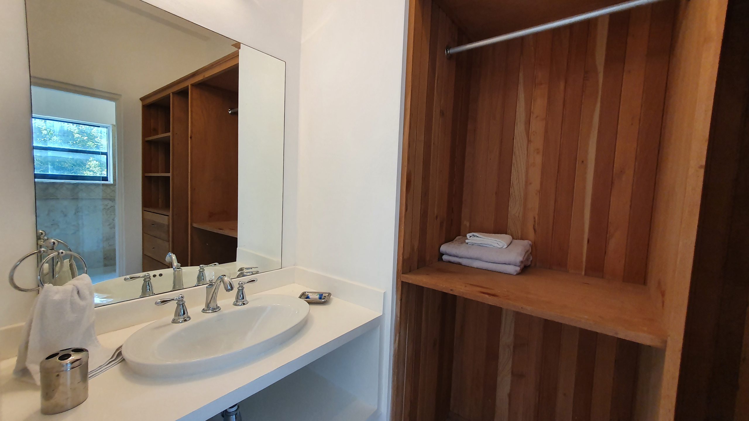 buyDRproperty Bathroom vanity with oval sink, large mirror, and built-in wooden closet Sosua Real Estate