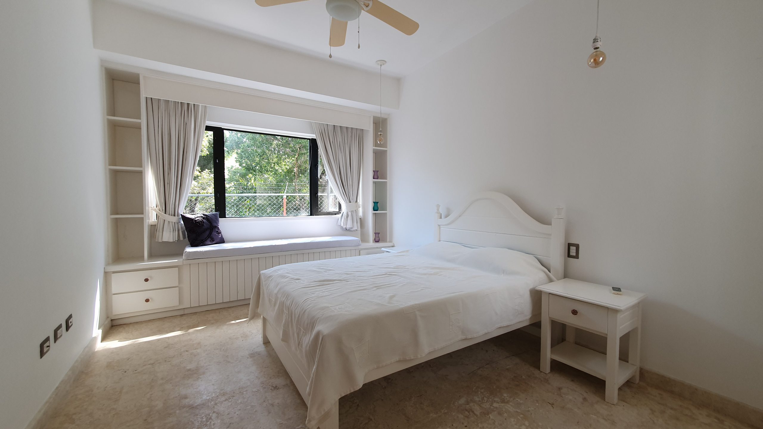 buyDRproperty Cozy white bedroom with window seat, bed, and natural light. Sosua Real Estate