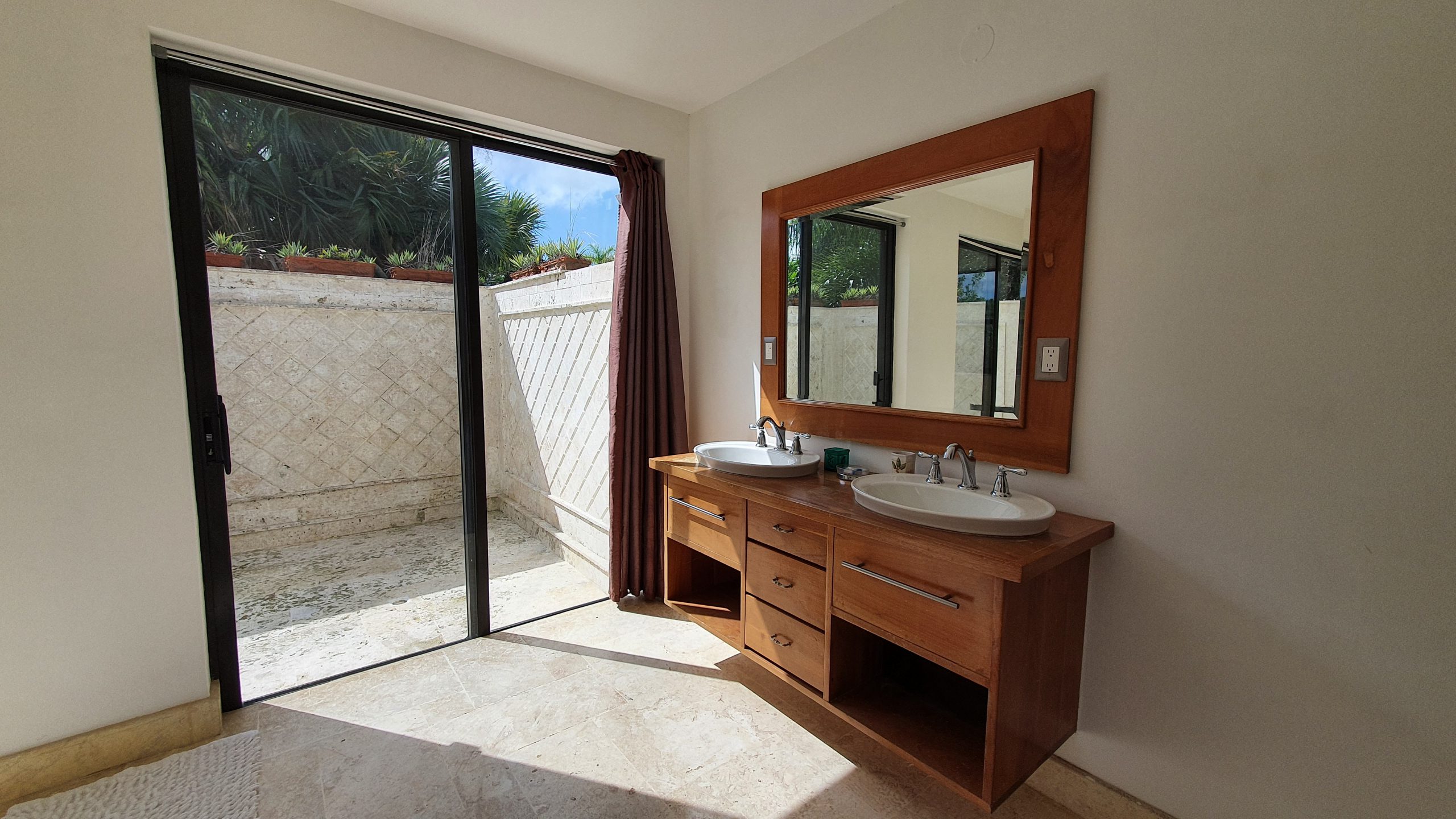 buyDRproperty Modern bathroom with double vanity, wood cabinet, and sliding door to outdoor space. Sosua Real Estate