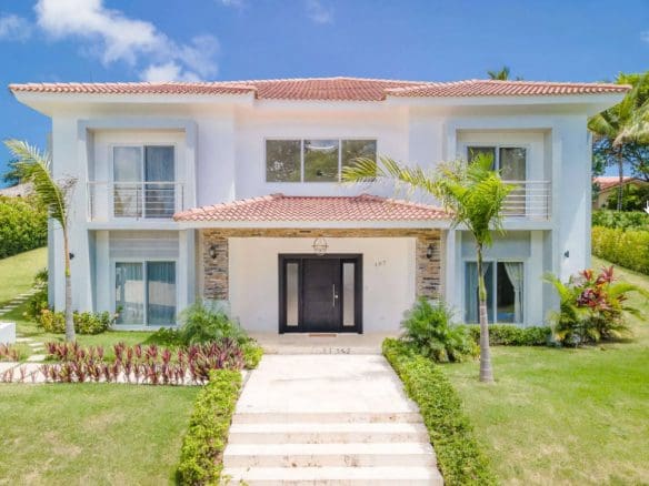 buyDRproperty Luxury two-story villa with a red tile roof and manicured lawn. Sosua Real Estate