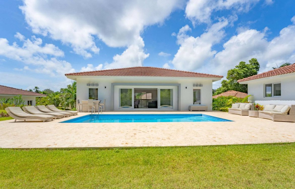 buyDRproperty Luxury villa with pool, lounge chairs, and outdoor seating under a blue sky Sosua Real Estate