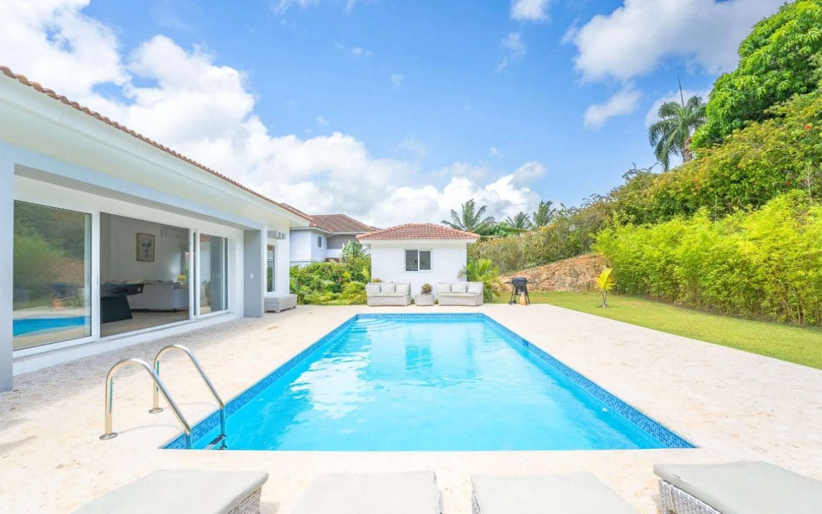 buyDRproperty Backyard pool with clear blue water, lounge chairs, and tropical landscaping. Sosua Real Estate