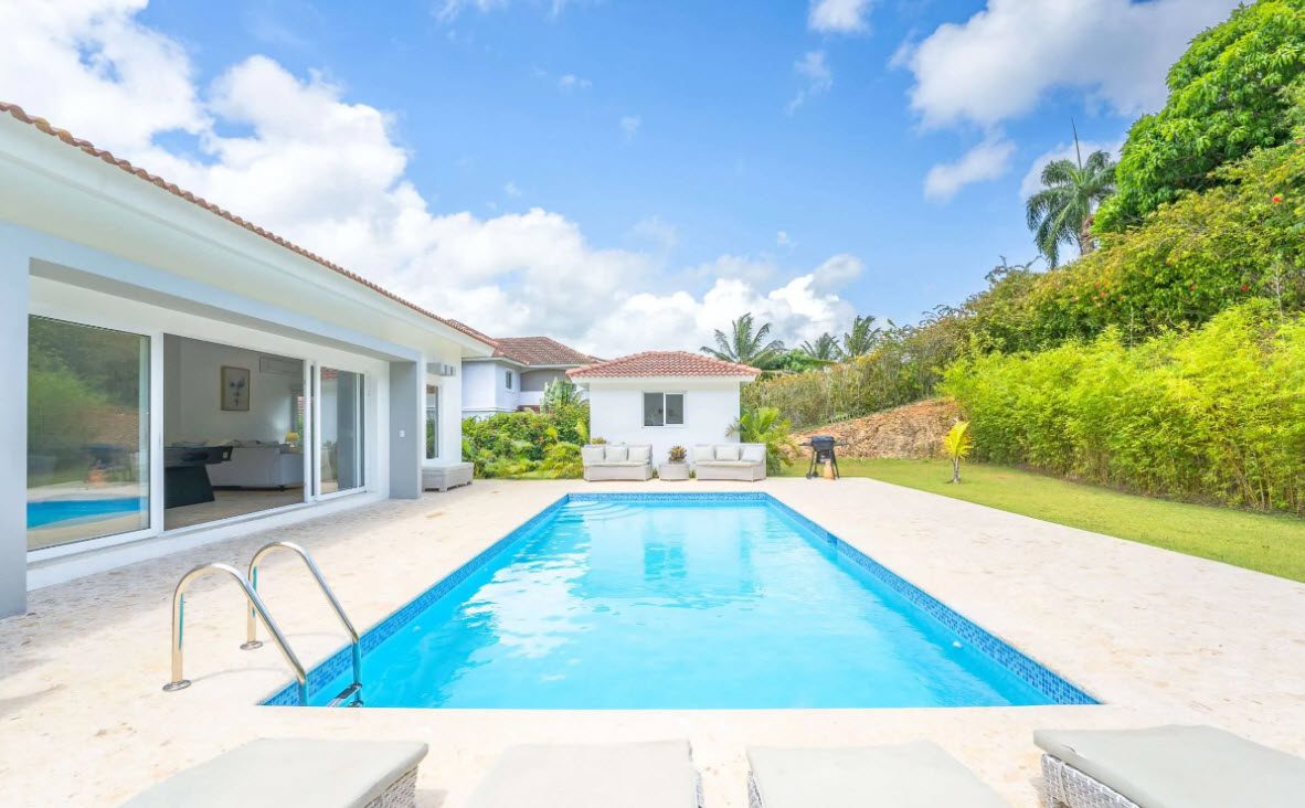 buyDRproperty Backyard pool with clear blue water, lounge chairs, and tropical landscaping. Sosua Real Estate