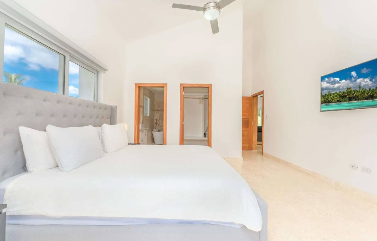 buyDRproperty Bright bedroom with king-size bed, ensuite bathroom, and tropical view on TV. Sosua Real Estate