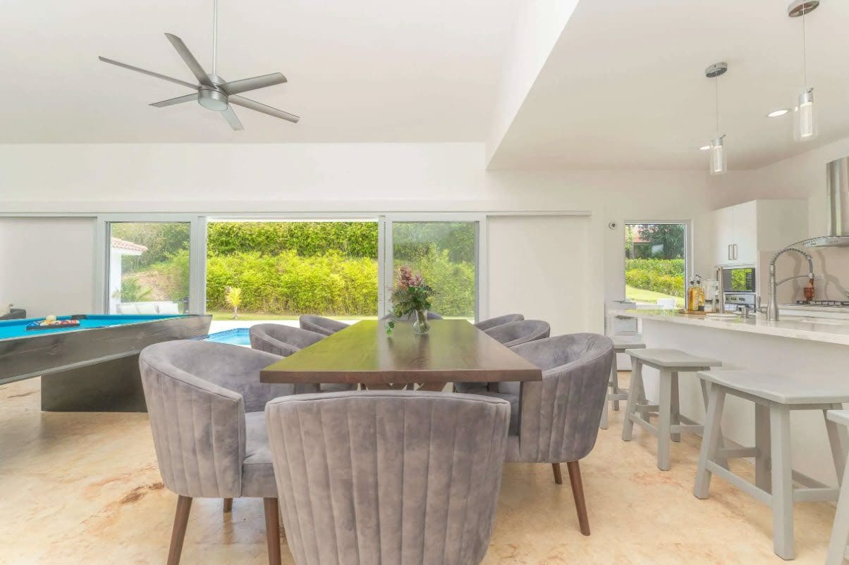 buyDRproperty Open-concept living space with dining table, pool table, and outdoor pool view. Sosua Real Estate