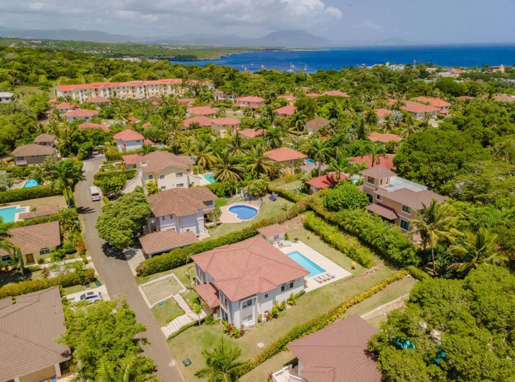 buyDRproperty Aerial view of luxury villas with pools in a tropical resort community near the coast. Sosua Real Estate