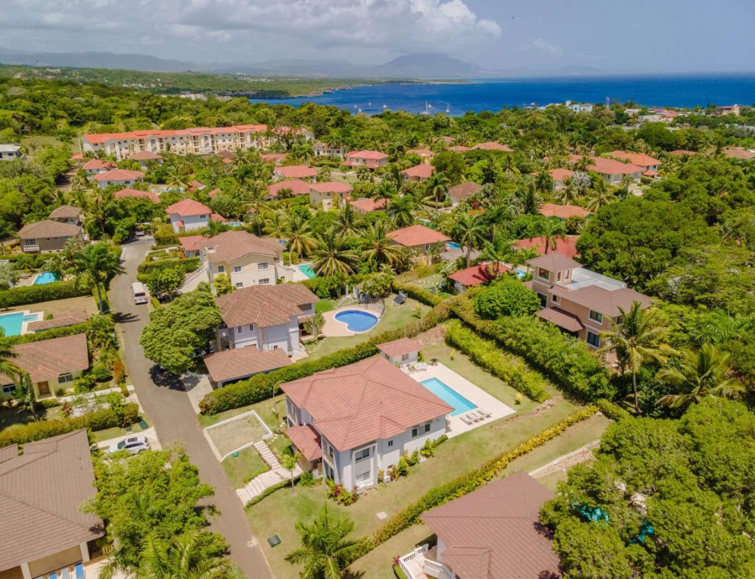 buyDRproperty Aerial view of luxury villas with pools in a tropical resort community near the coast. Sosua Real Estate