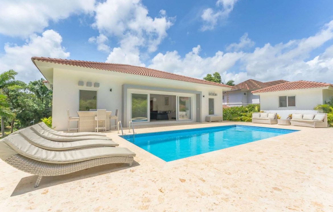 buyDRproperty Luxury villa with private pool, lounge chairs, and outdoor seating under a sunny sky. Sosua Real Estate