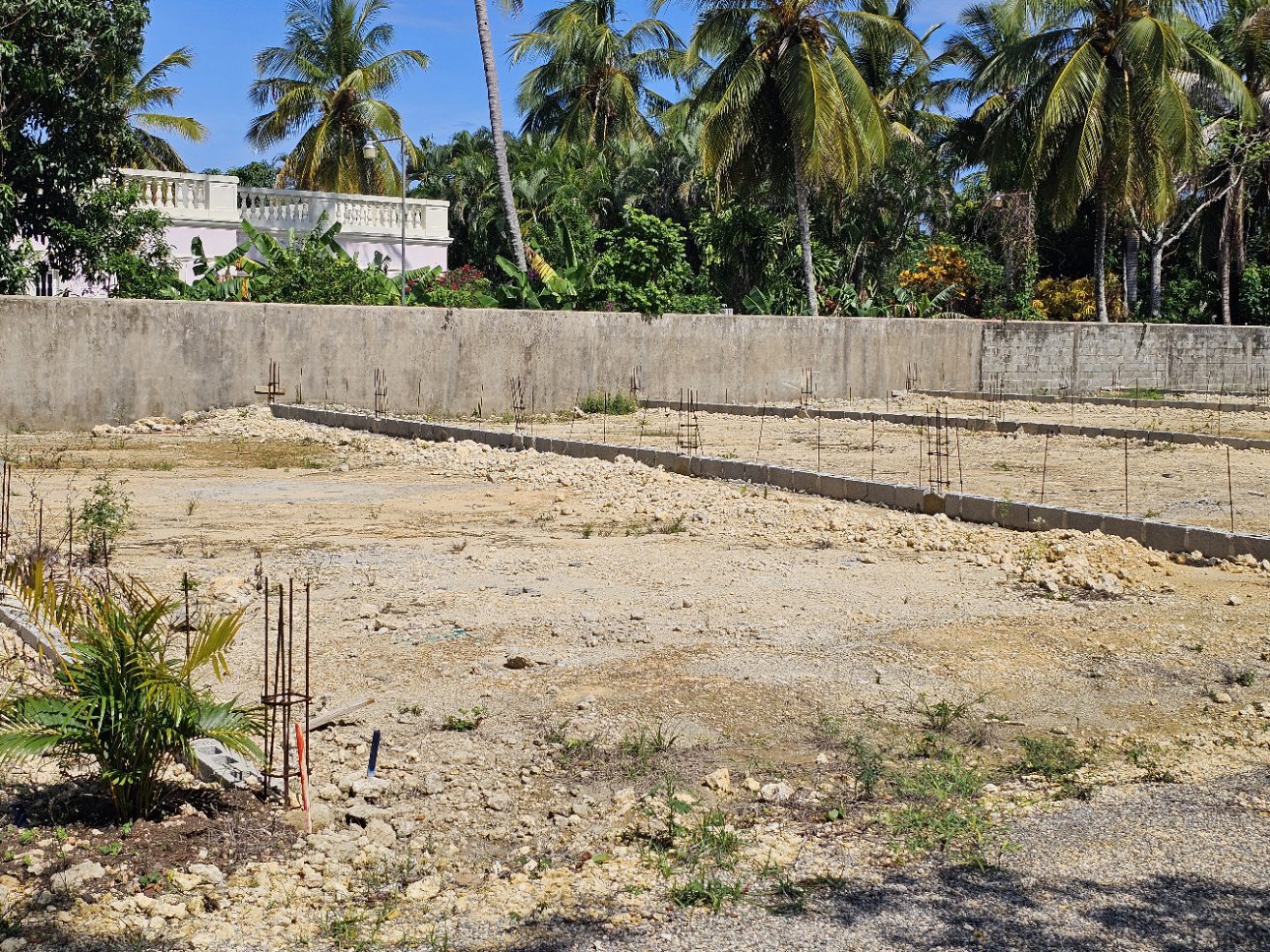 buyDRproperty Construction site with foundation and rebar, tropical trees in background. Sosua Real Estate