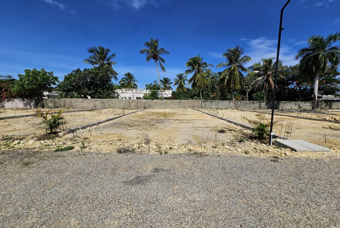 buyDRproperty Cleared land ready for construction in a tropical setting with palm trees and blue sky. Sosua Real Estate