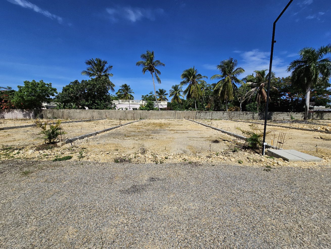 buyDRproperty Cleared land ready for construction in a tropical setting with palm trees and blue sky. Sosua Real Estate