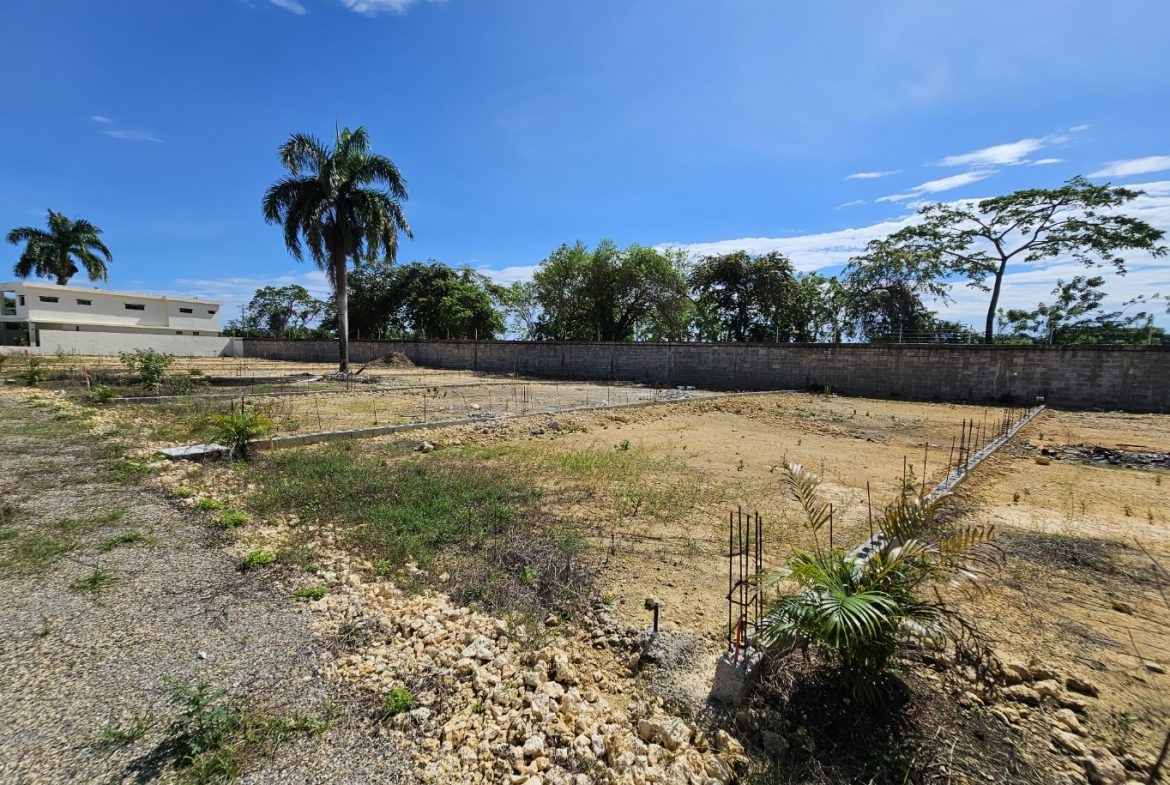 buyDRproperty Construction site with foundation work, palm trees, and blue sky. Sosua Real Estate
