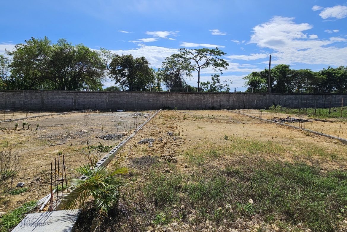 buyDRproperty Cleared land ready for construction, with a block wall in the background under a blue sky. Sosua Real Estate