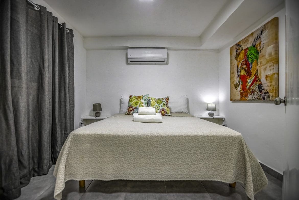 buyDRproperty Cozy bedroom with a queen bed, colorful pillows, and modern art. Sosua Real Estate
