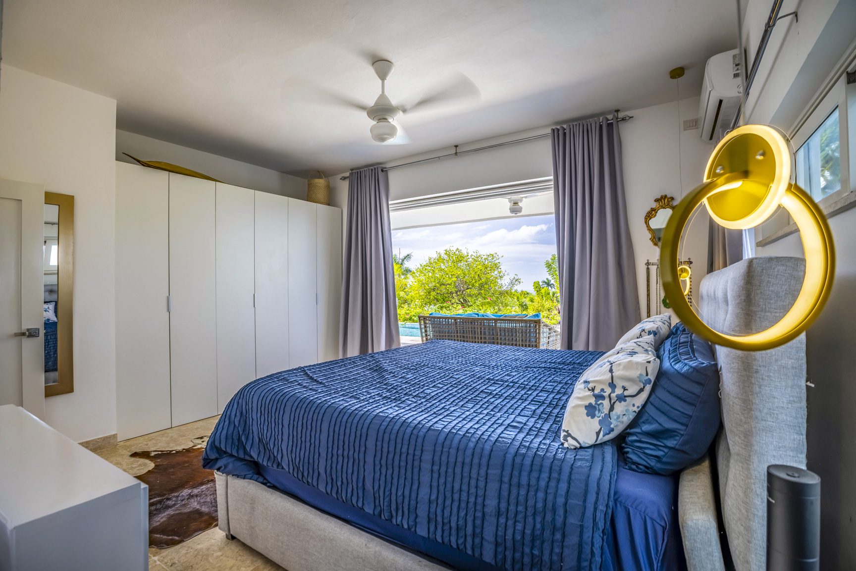 buyDRproperty Bedroom with blue bedding, white wardrobe, and pool view Sosua Real Estate