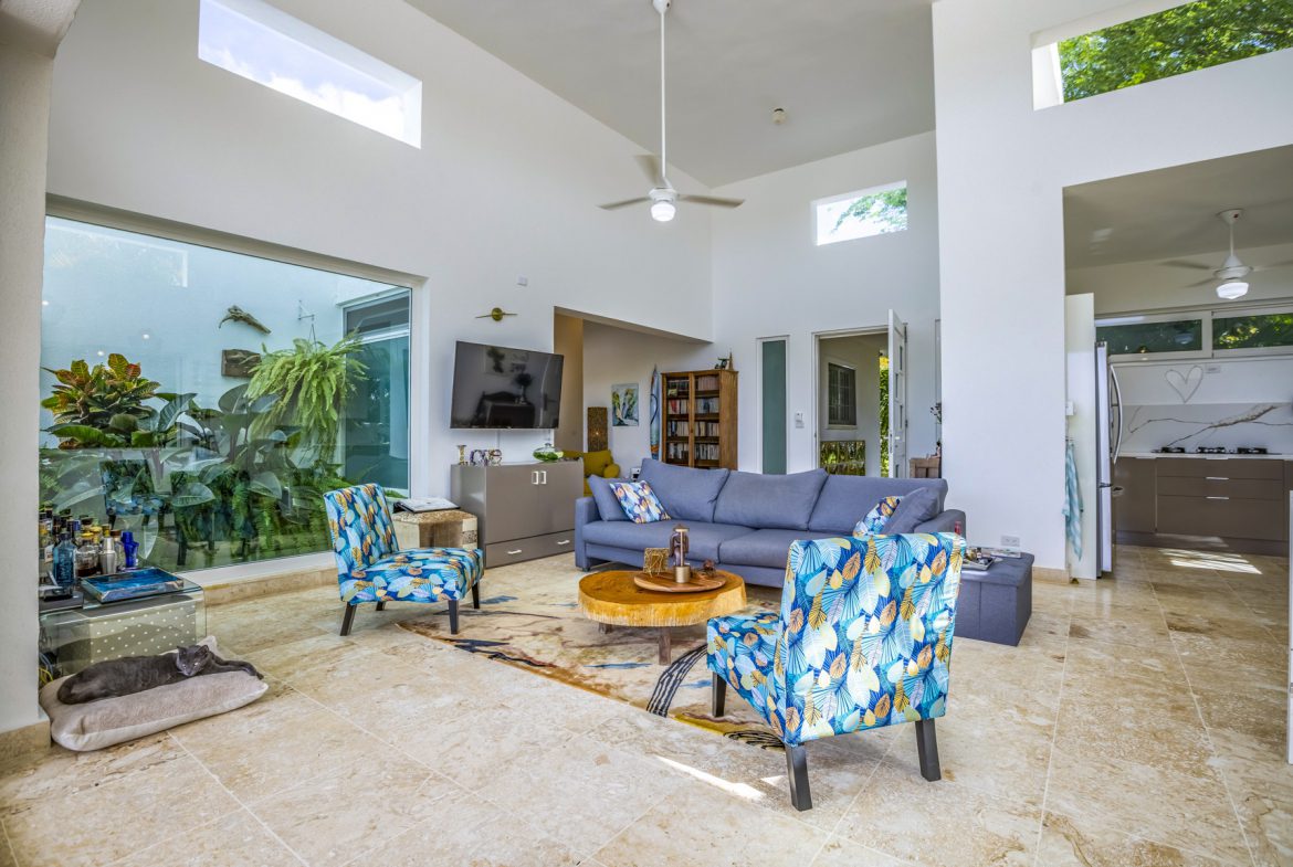 buyDRproperty Cozy living room with blue sofa, patterned chairs, and indoor plants. Sosua Real Estate