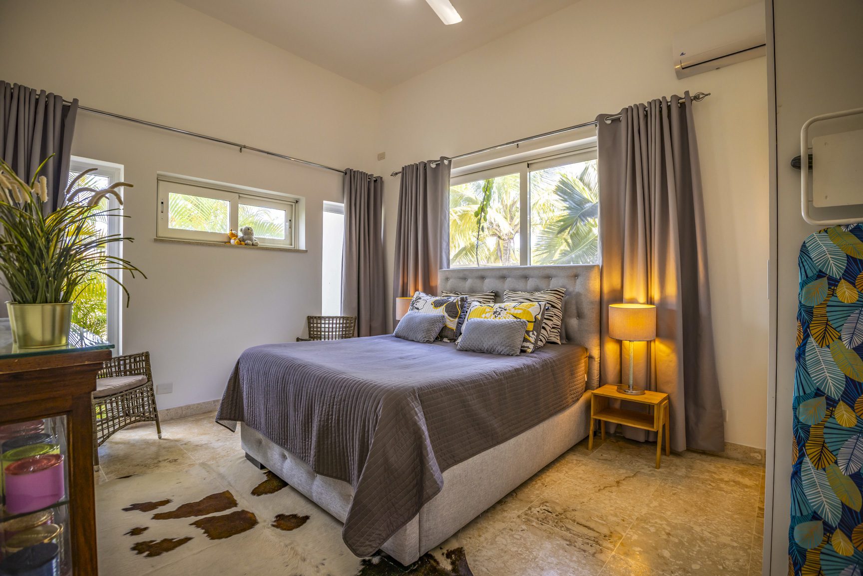 buyDRproperty Bright bedroom with a gray bed, curtains, and tropical view. Sosua Real Estate