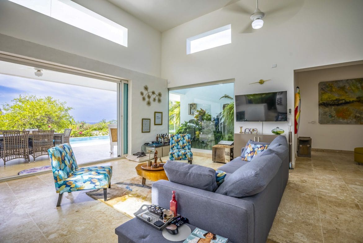 buyDRproperty Spacious living room with gray sofa, open patio view, and modern decor Sosua Real Estate