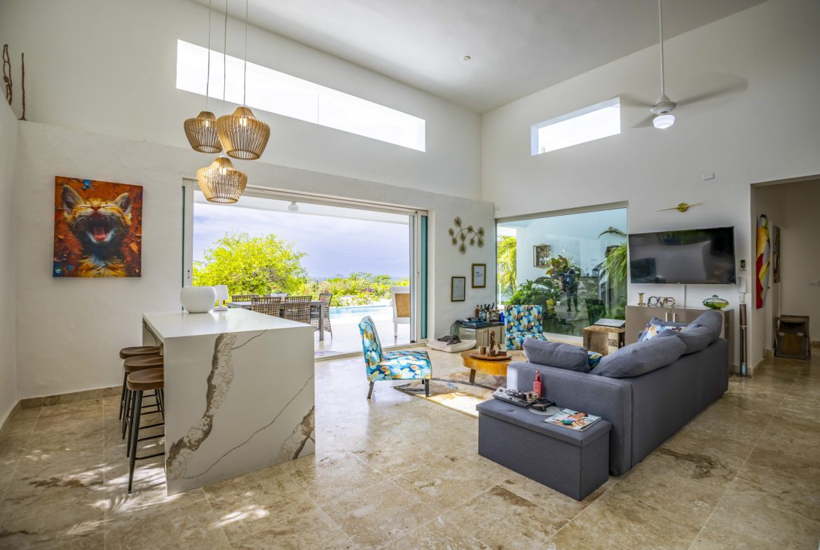 buyDRproperty Bright, modern living room with pool view through open sliding doors. Sosua Real Estate