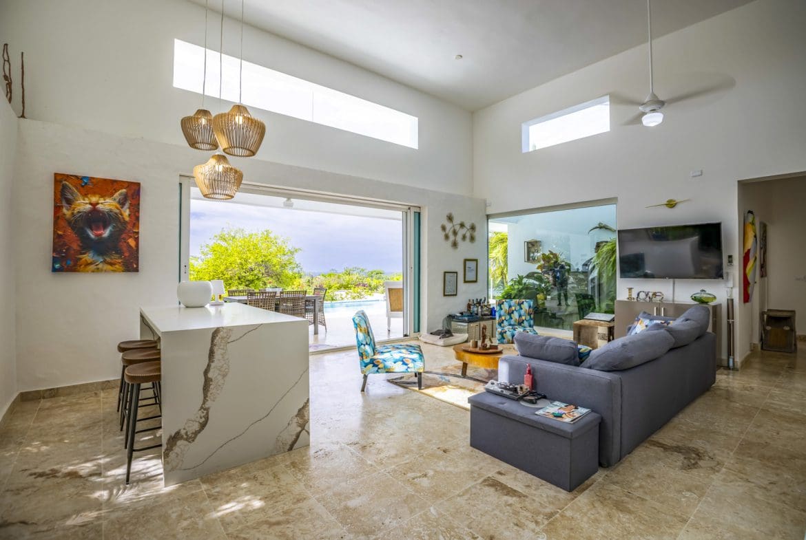 buyDRproperty Bright, modern living room with pool view through open sliding doors. Sosua Real Estate