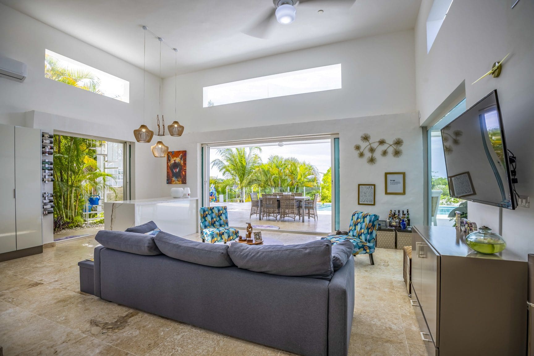 buyDRproperty Spacious living room with a large gray sofa, modern decor, and open access to patio garden Sosua Real Estate