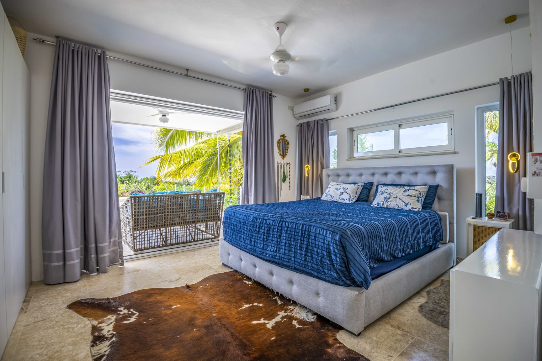 buyDRproperty Bright bedroom with blue bedding, balcony, and cowhide rug. Sosua Real Estate