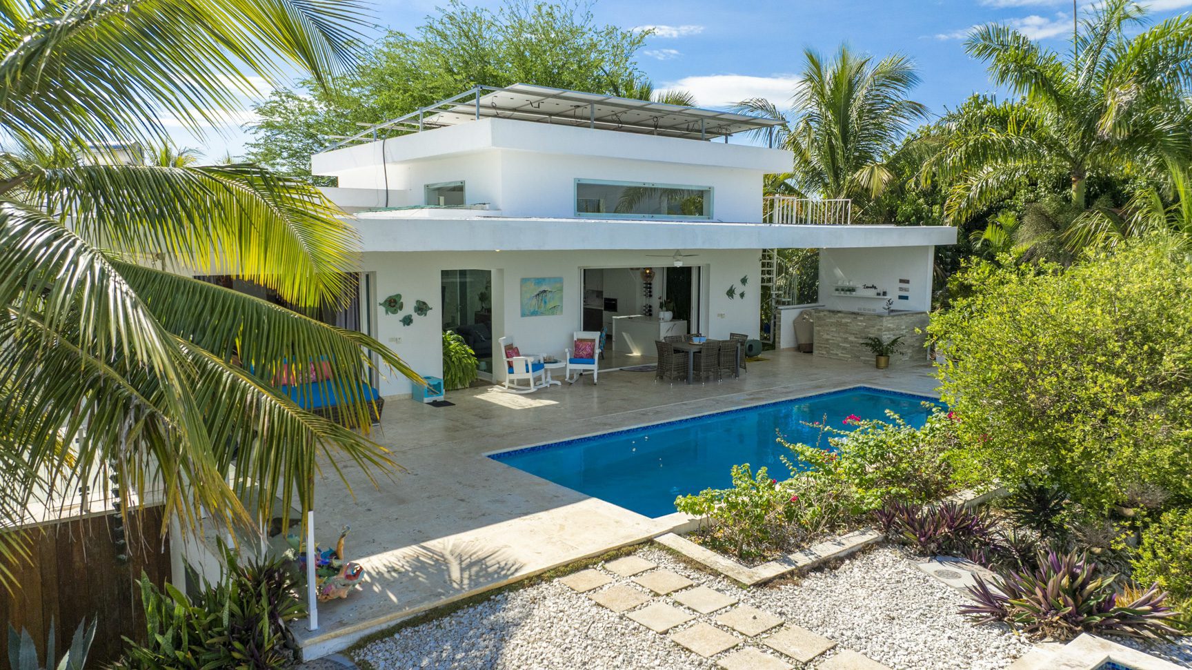 buyDRproperty Modern white villa with pool, palm trees, and solar panels Sosua Real Estate