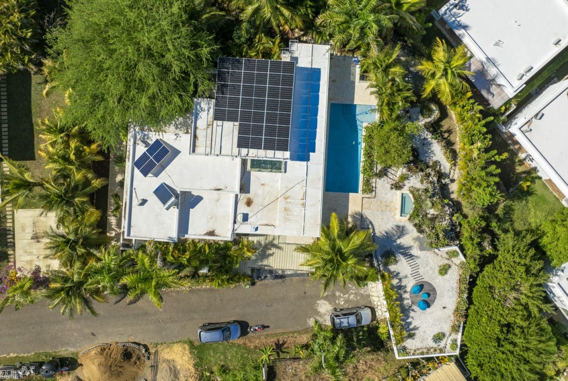 buyDRproperty Aerial view of modern villas with solar panels and pools amidst lush tropical greenery. Sosua Real Estate