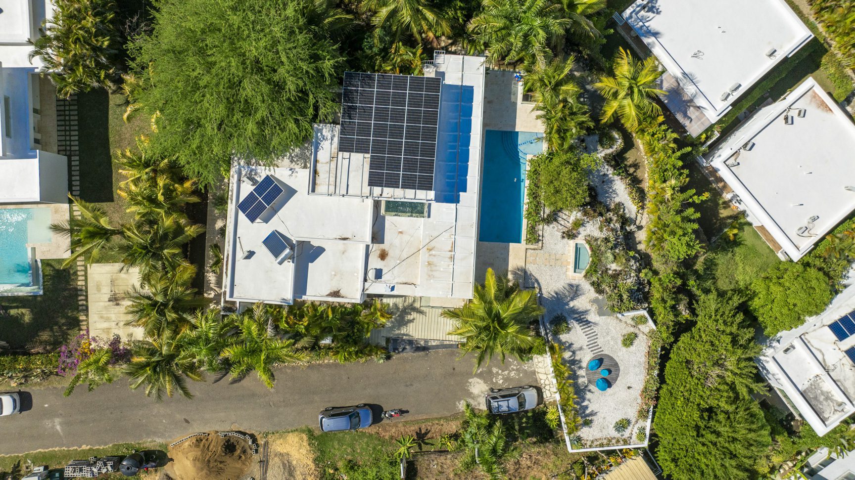 buyDRproperty Aerial view of modern villas with solar panels and pools amidst lush tropical greenery. Sosua Real Estate