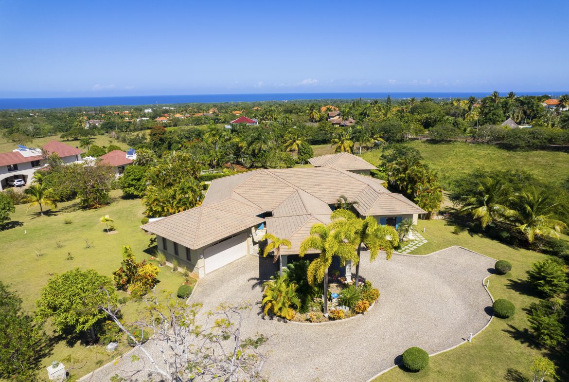 buyDRproperty Spacious villa with manicured lawn and ocean view under clear blue sky Sosua Real Estate