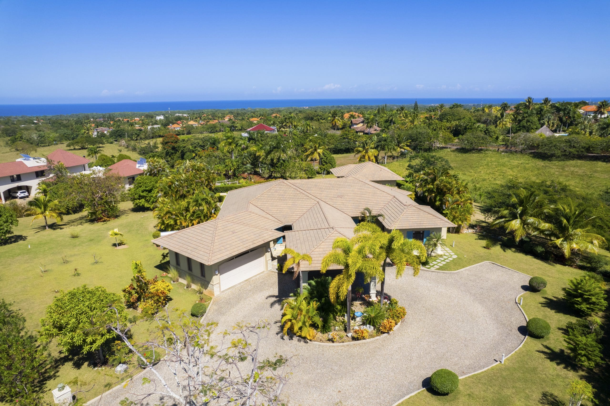 buyDRproperty Spacious villa with manicured lawn and ocean view under clear blue sky Sosua Real Estate