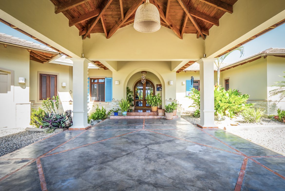 buyDRproperty Covered patio entrance with tropical plants and arched doorway Sosua Real Estate