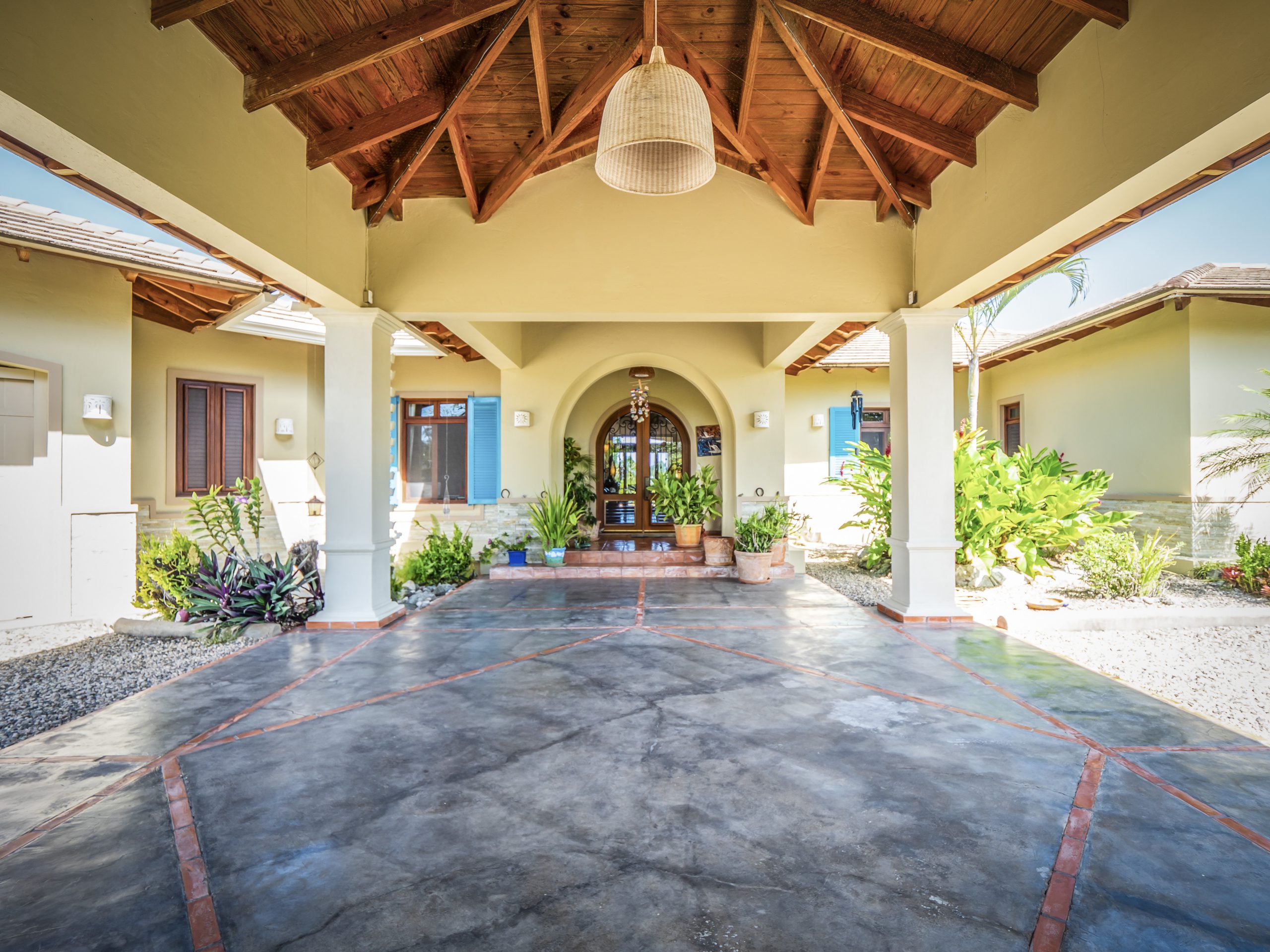 buyDRproperty Covered patio entrance with tropical plants and arched doorway Sosua Real Estate
