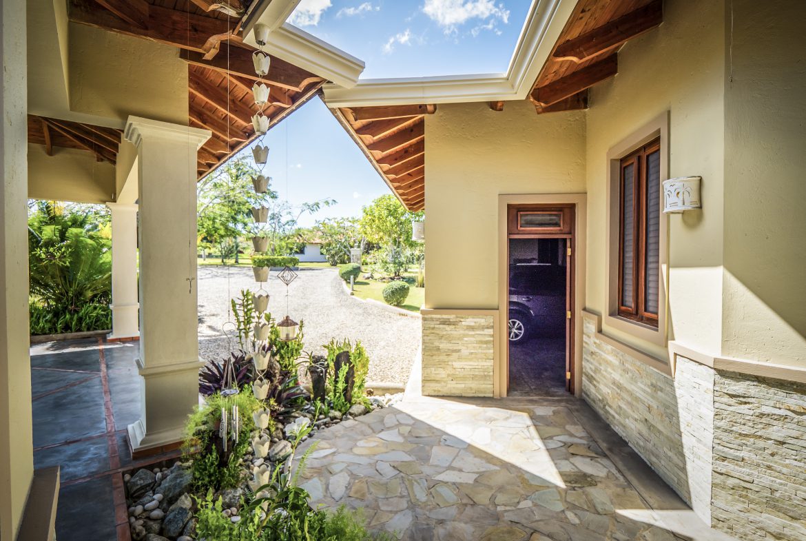 buyDRproperty Sunny patio entrance with stone flooring and garden plants Sosua Real Estate