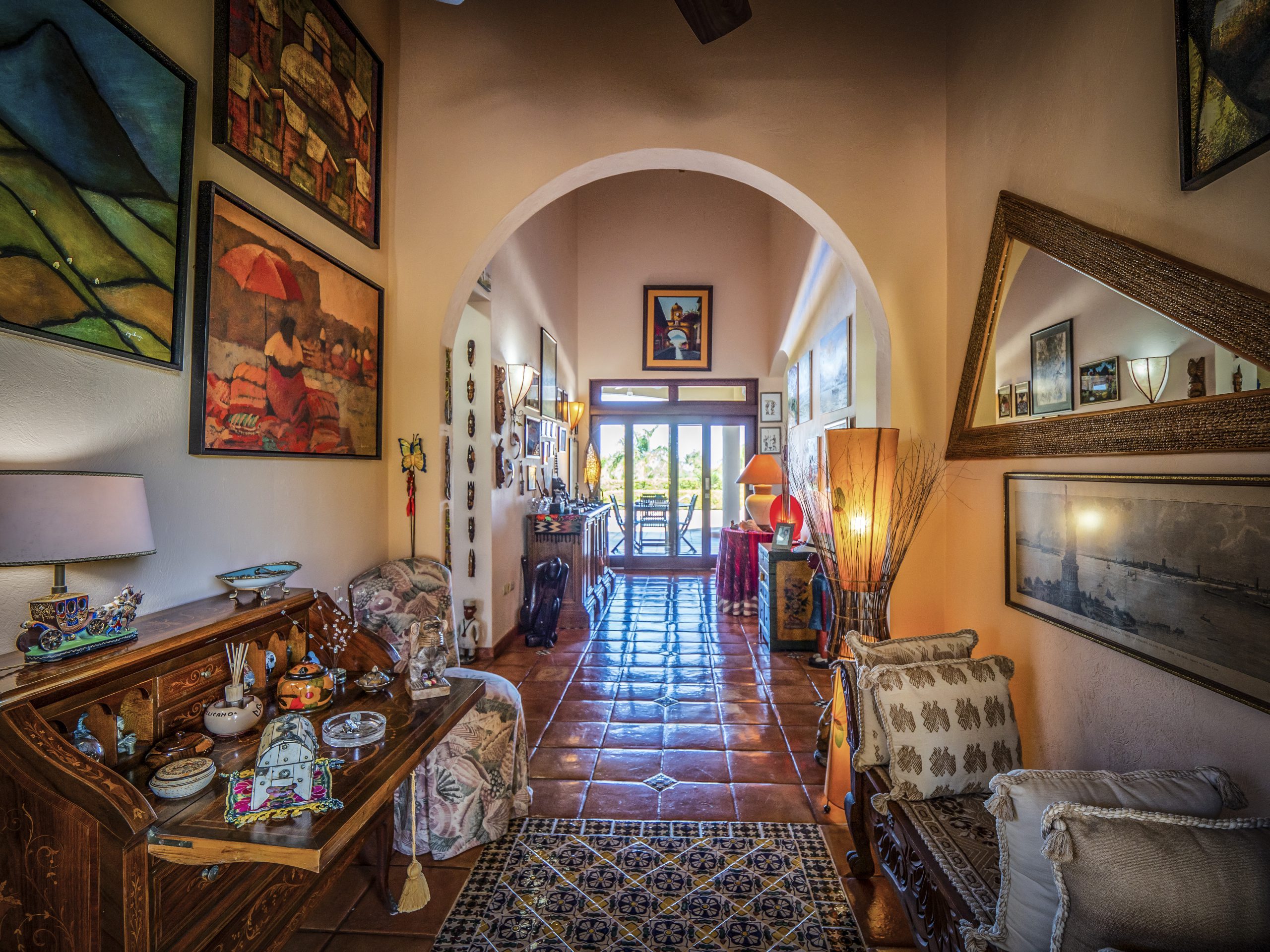 buyDRproperty Colorful, art-filled hallway with arched entry and sunlight at the end Sosua Real Estate