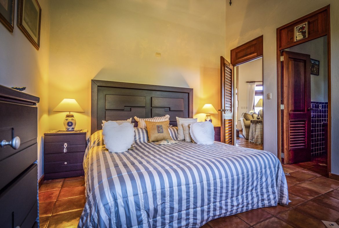 buyDRproperty Cozy bedroom with a striped bedspread and warm lighting Sosua Real Estate