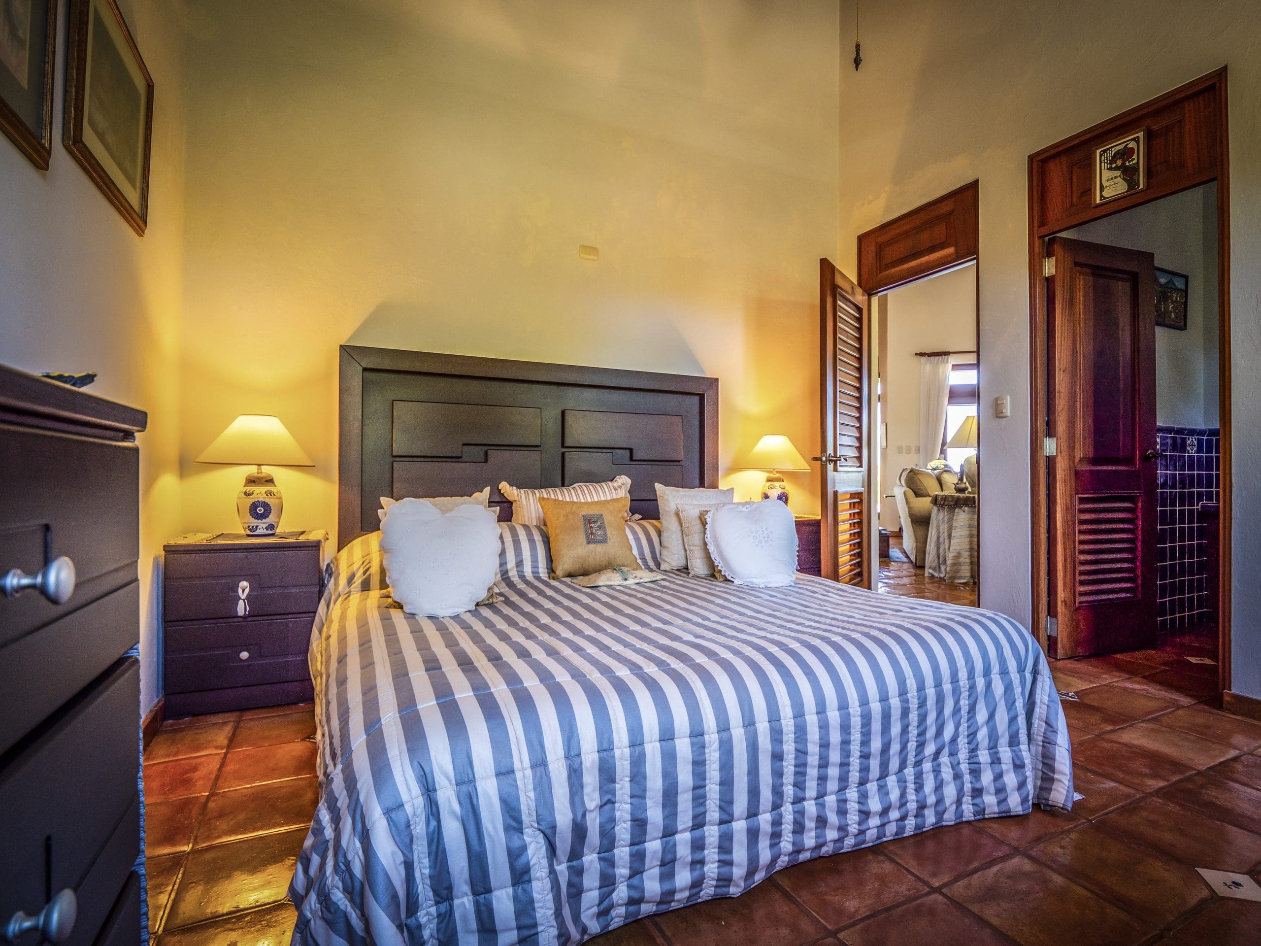 buyDRproperty Cozy bedroom with a striped bedspread and warm lighting Sosua Real Estate